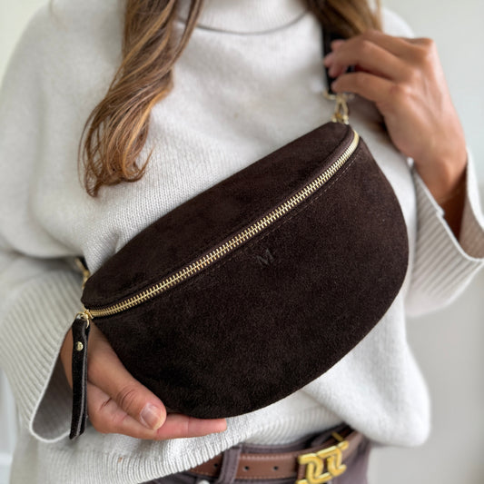Woman wearing a brown suede fanny pack with a gold zipper.