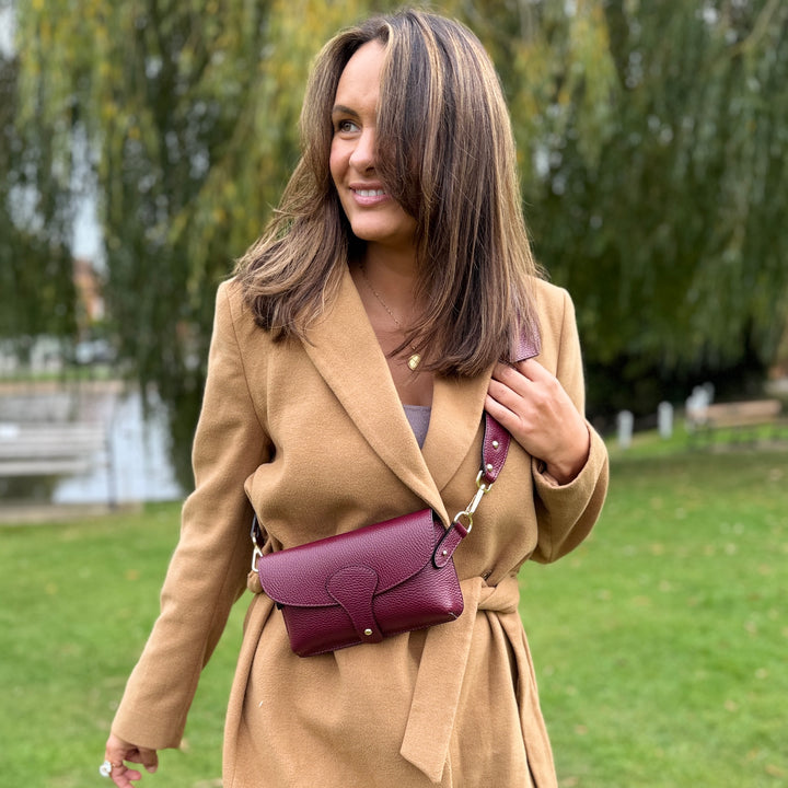 burgundy handbag worn as crossbody 
